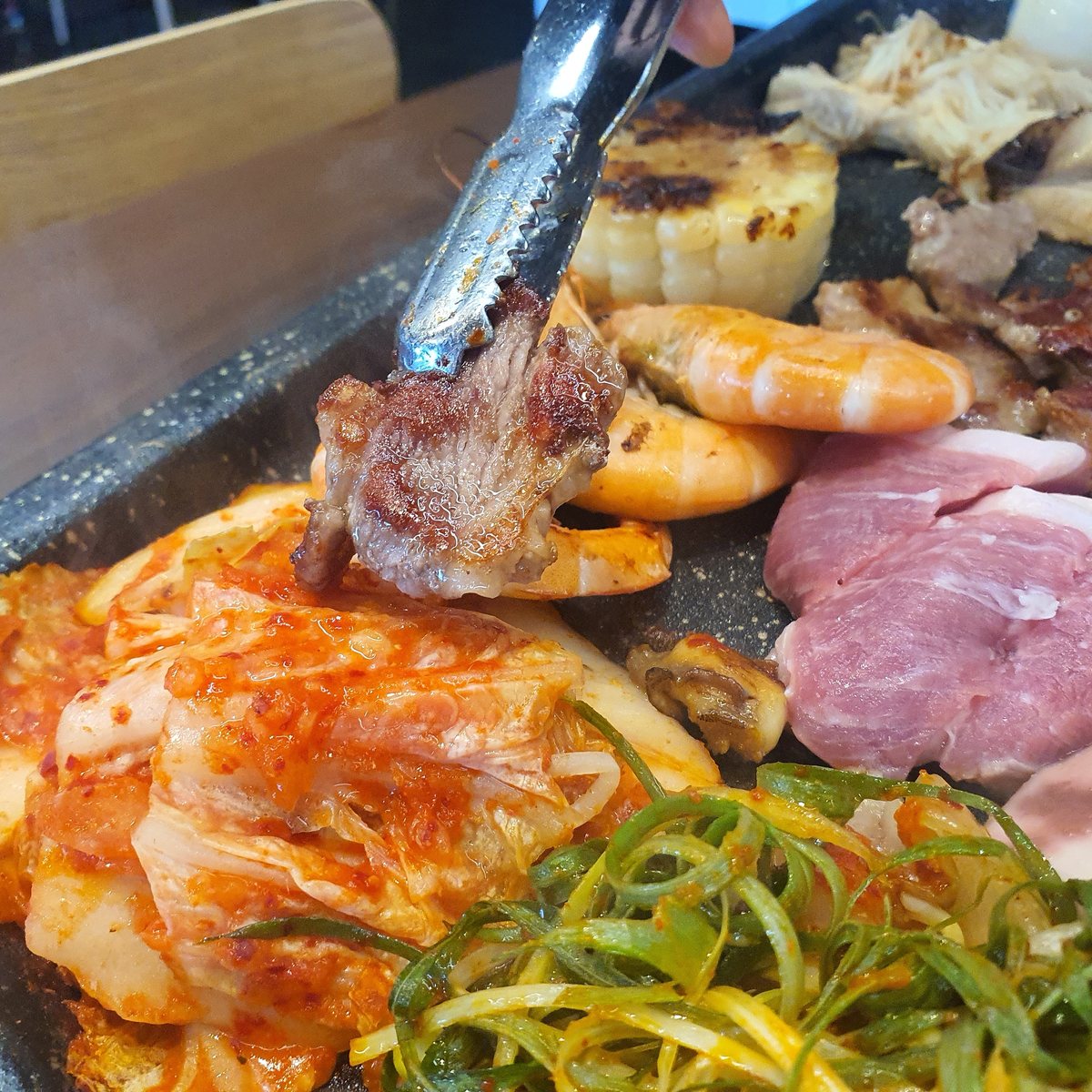 흑돼지 해물삼합 — 불판 위에 흑돼지·새우·김치·파채를 함께 굽는 모습