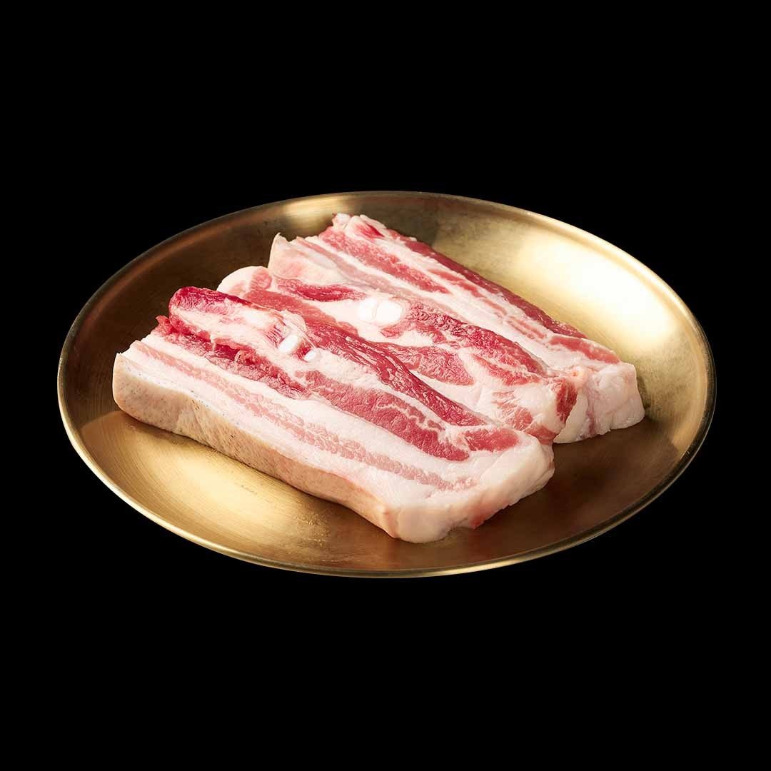 숙성 흑오겹살 — 놋접시에 담은 두툼한 오겹살 생고기