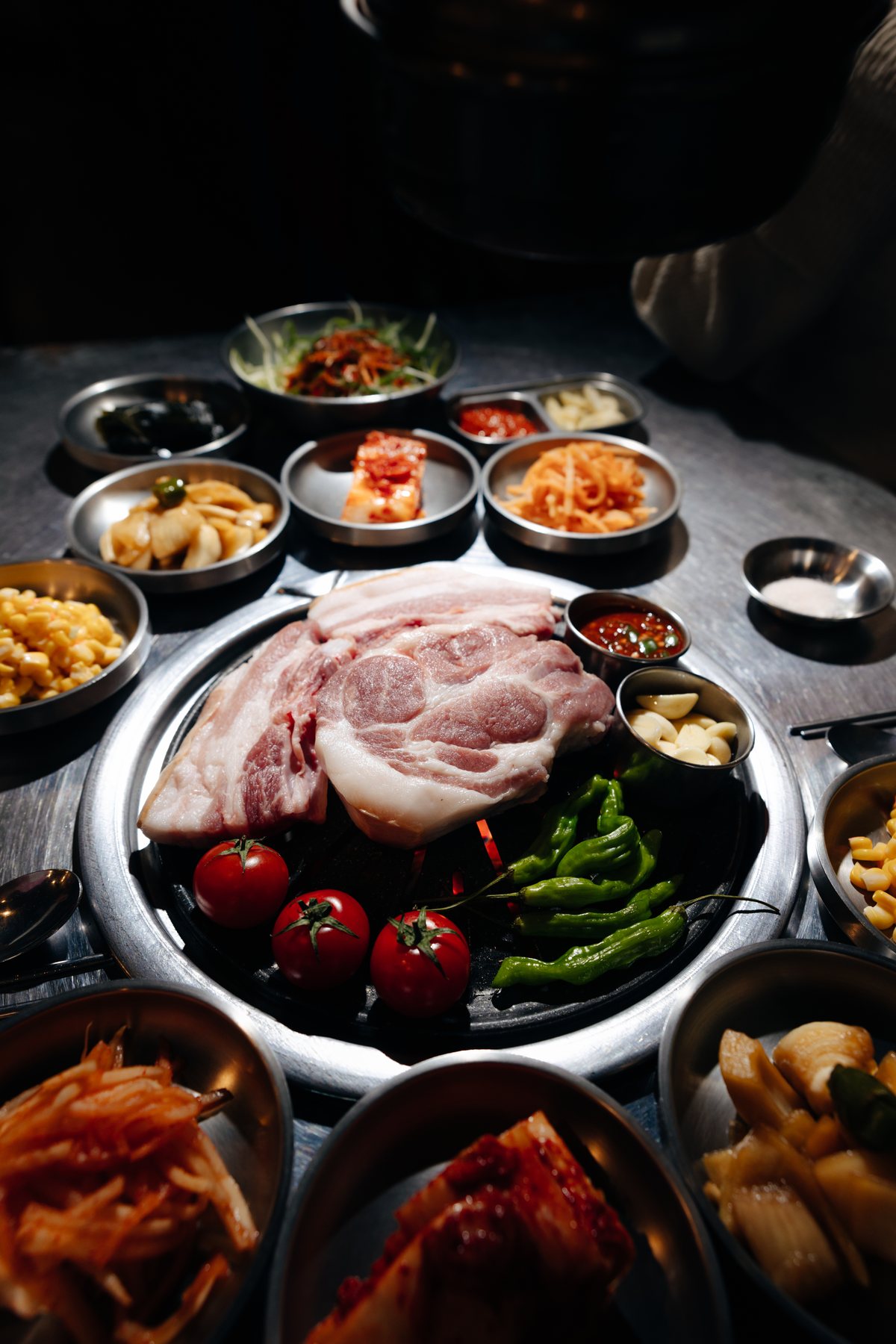 불판 가운데 생고기와 방울토마토·고추를 올리고 반찬을 둘러 차린 상