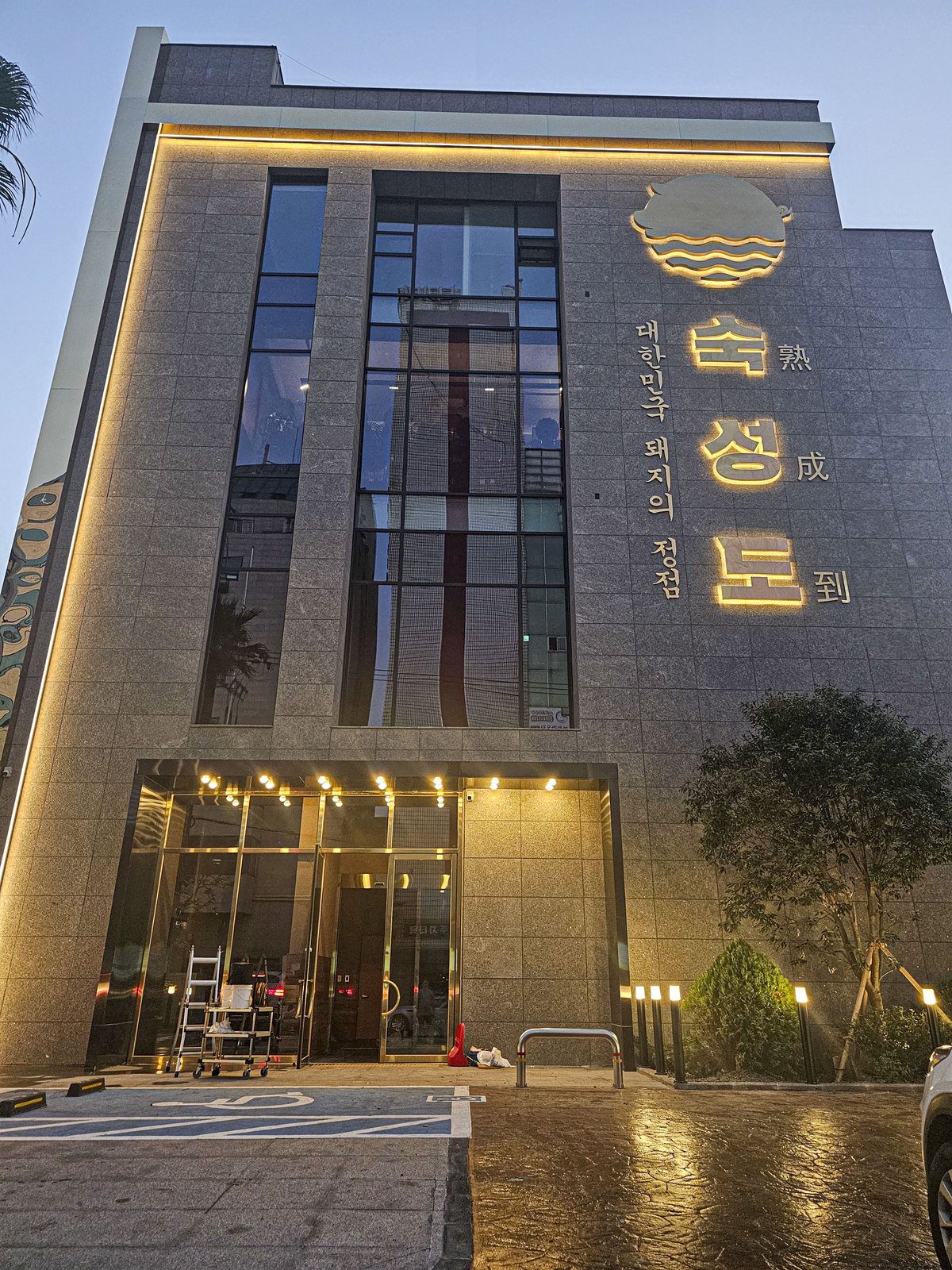 숙성도 제주본점 — 금색 '숙성도' 간판이 달린 회색 석재 건물 외관(저녁)