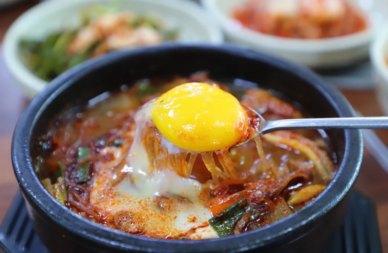 뚝배기 해장국에서 달걀노른자를 숟가락으로 떠 올린 모습