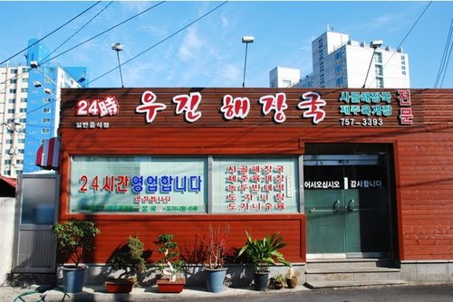 우진해장국 — '24시간 영업합니다' 문구가 붙은 붉은 간판의 단층 가게 외관